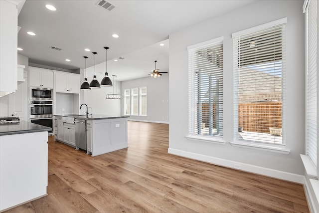 kitchen featuring dark countertops, open floor plan, visible vents, and a sink