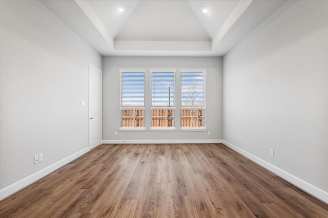 spare room featuring high vaulted ceiling, baseboards, and wood finished floors