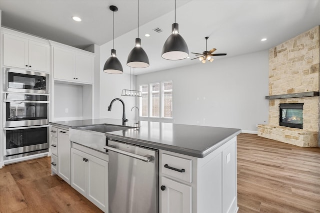 kitchen featuring visible vents, a sink, dark countertops, stainless steel appliances, and a fireplace