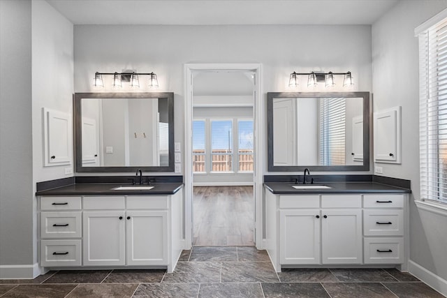 bathroom with two vanities, a wealth of natural light, and a sink