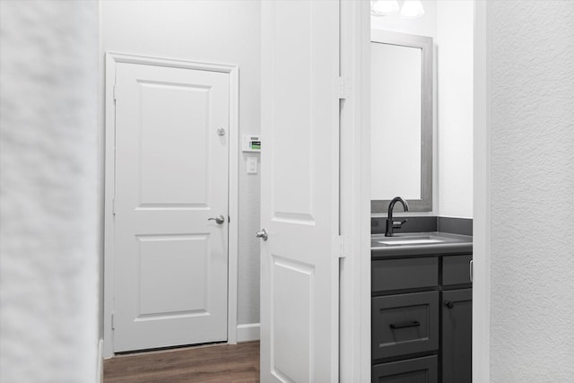 bathroom with vanity, wood finished floors, and a textured wall