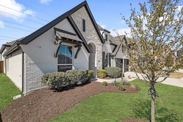 view of front facade featuring a front lawn, driveway, brick siding, and stone siding