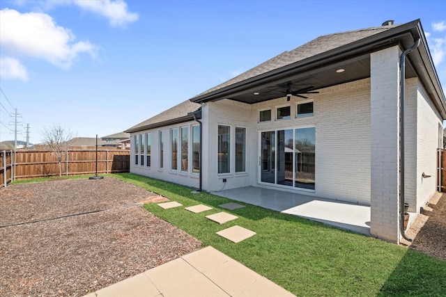 rear view of property featuring brick siding, ceiling fan, a lawn, a fenced backyard, and a patio