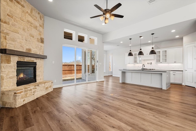 unfurnished living room featuring a stone fireplace, wood finished floors, and a ceiling fan