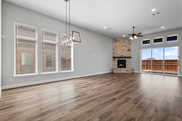 unfurnished living room with a ceiling fan, wood finished floors, visible vents, baseboards, and a fireplace