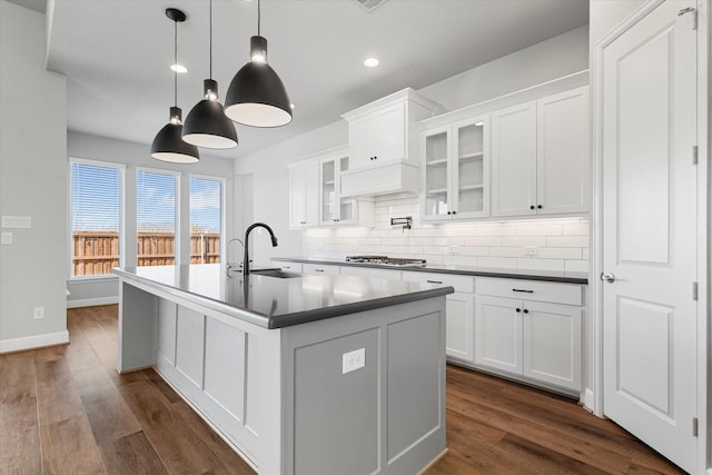 kitchen with a center island with sink, stainless steel gas cooktop, a sink, white cabinets, and tasteful backsplash