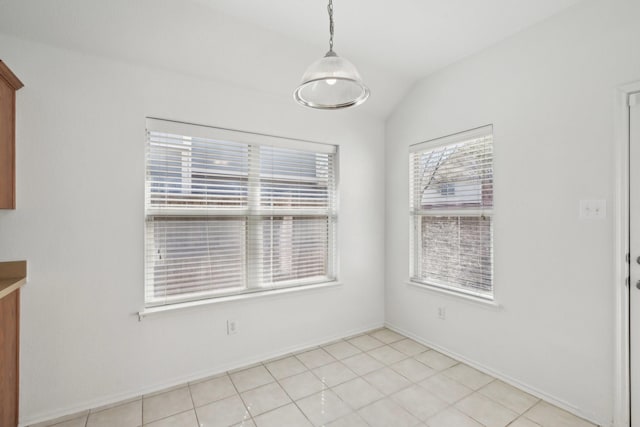 unfurnished dining area with vaulted ceiling, baseboards, and light tile patterned floors