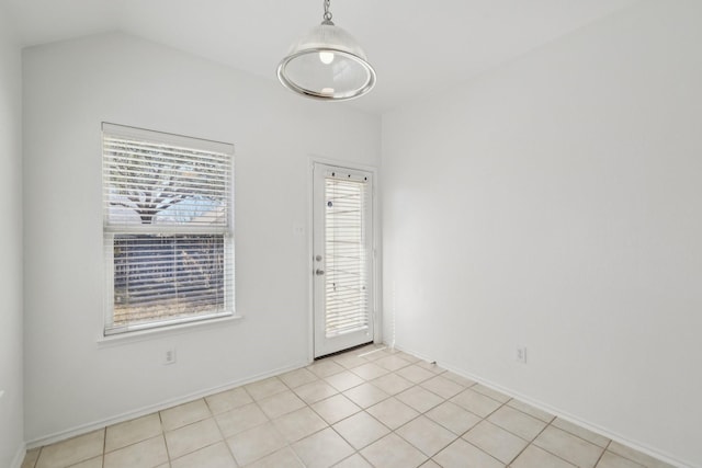 spare room featuring a healthy amount of sunlight, baseboards, and vaulted ceiling