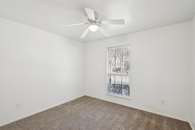 carpeted empty room with ceiling fan and baseboards