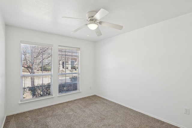 carpeted spare room with a healthy amount of sunlight, baseboards, and a ceiling fan