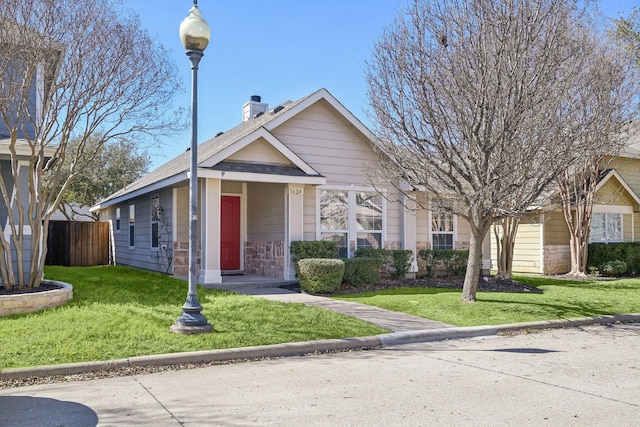 view of front facade featuring a chimney, fence, and a front lawn