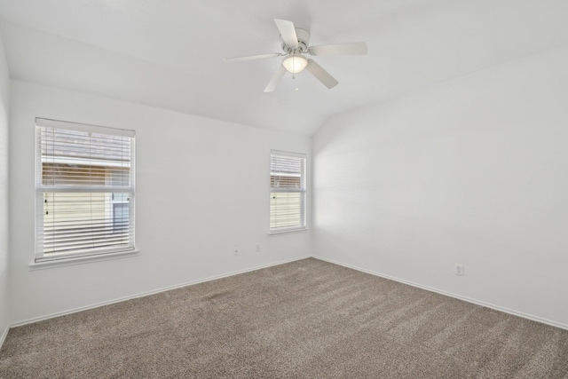 empty room featuring carpet floors, vaulted ceiling, baseboards, and ceiling fan