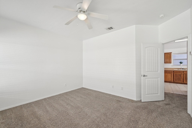 empty room featuring light colored carpet, visible vents, a sink, and ceiling fan