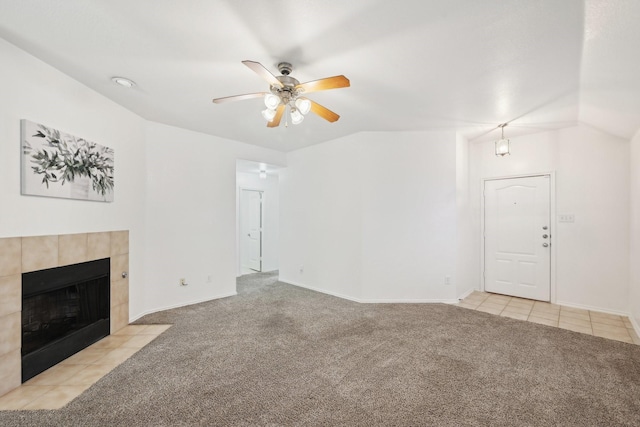 unfurnished living room with light tile patterned floors, light colored carpet, a ceiling fan, vaulted ceiling, and a tile fireplace