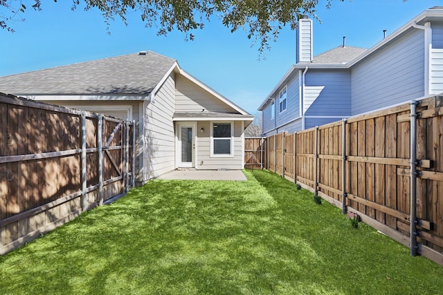 rear view of house with a shingled roof, a lawn, a chimney, and a fenced backyard