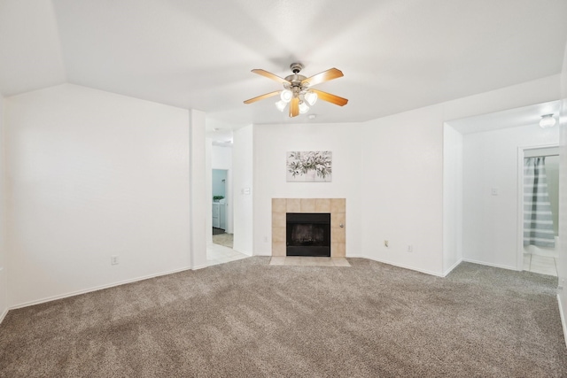 unfurnished living room with baseboards, a tile fireplace, lofted ceiling, ceiling fan, and carpet flooring