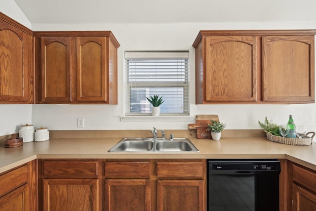 kitchen with brown cabinetry, black dishwasher, light countertops, and a sink