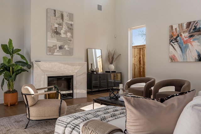 living area with visible vents, wood finished floors, and a high end fireplace