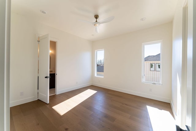 unfurnished room with dark wood-style floors, ceiling fan, and baseboards