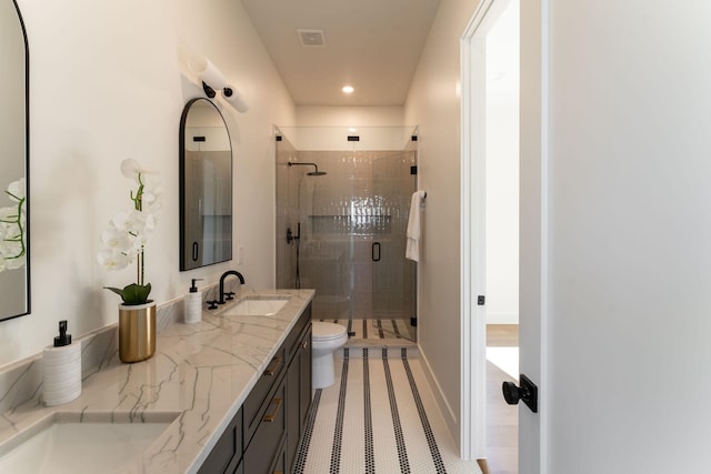 full bath with double vanity, a stall shower, a sink, and toilet