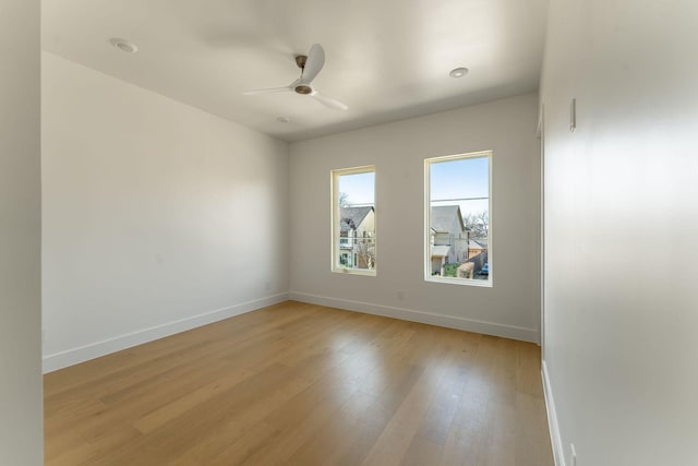 spare room featuring ceiling fan, light wood-style flooring, and baseboards