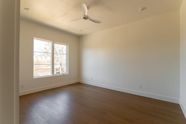 empty room featuring dark wood finished floors, baseboards, and ceiling fan