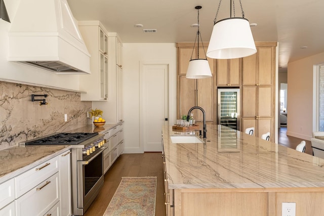 kitchen featuring visible vents, a spacious island, high end range, custom exhaust hood, and a sink