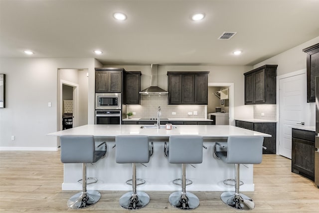 kitchen featuring stainless steel appliances, light countertops, visible vents, and wall chimney range hood