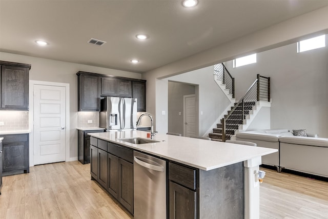 kitchen featuring visible vents, light wood-style flooring, stainless steel appliances, light countertops, and a sink