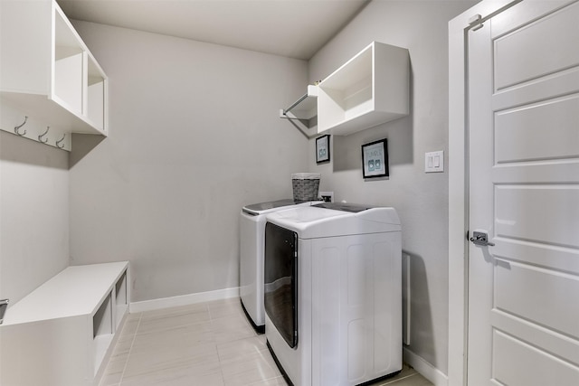 washroom with light tile patterned floors, laundry area, washer and clothes dryer, and baseboards