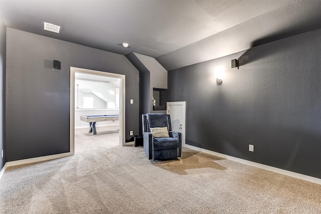 sitting room featuring visible vents, a textured wall, carpet flooring, vaulted ceiling, and baseboards