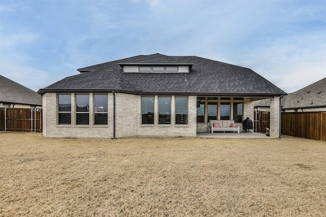 rear view of house featuring a patio area, a fenced backyard, brick siding, and roof with shingles