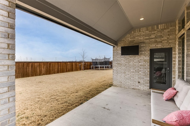 view of patio featuring a trampoline and fence