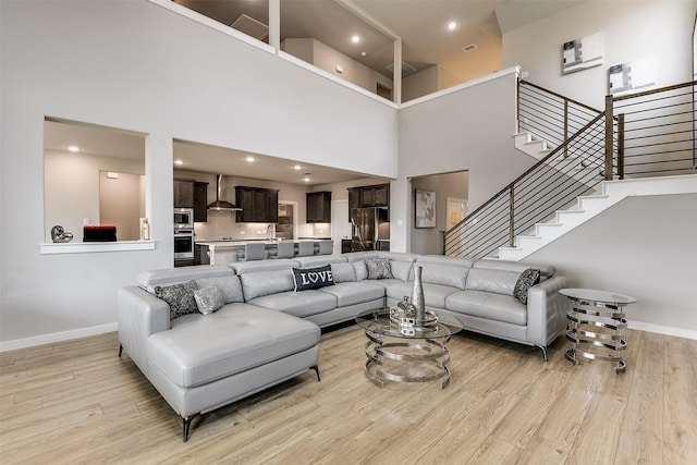 living area with light wood-style floors, stairway, and baseboards