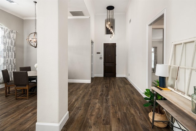 foyer entrance featuring baseboards, ornamental molding, dark wood-type flooring, and a notable chandelier