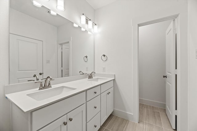 full bathroom featuring double vanity, a sink, and baseboards