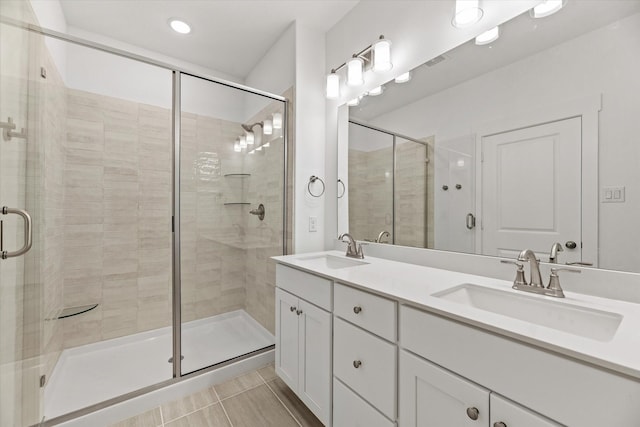 bathroom featuring double vanity, a stall shower, and a sink