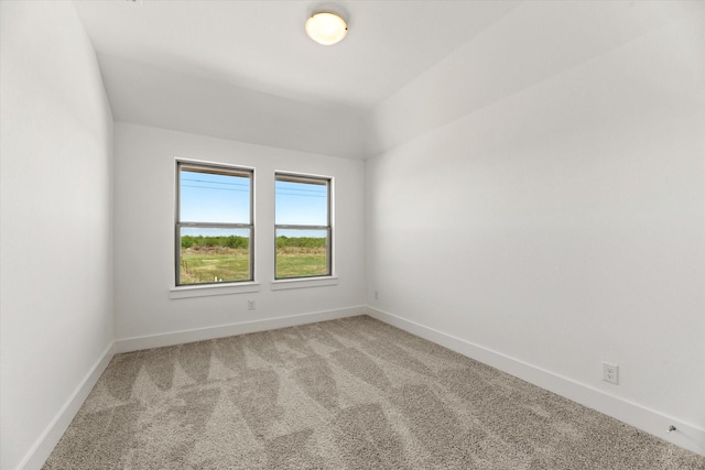 spare room with baseboards and light colored carpet