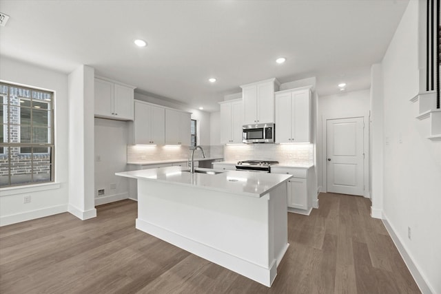 kitchen with appliances with stainless steel finishes, decorative backsplash, a sink, and white cabinets