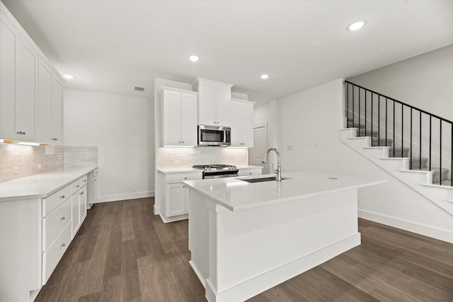 kitchen featuring recessed lighting, stainless steel appliances, dark wood-style flooring, a sink, and baseboards