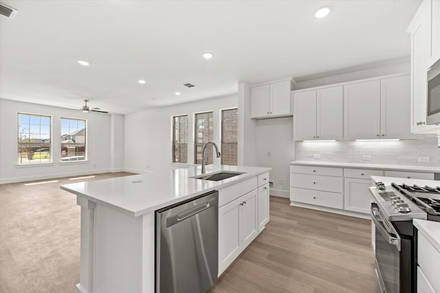 kitchen featuring tasteful backsplash, light countertops, appliances with stainless steel finishes, a sink, and light wood-type flooring