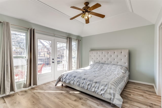 bedroom featuring access to outside, a raised ceiling, wood finished floors, and french doors