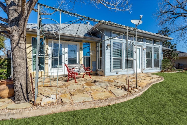 rear view of house featuring french doors, a patio area, a yard, and roof with shingles