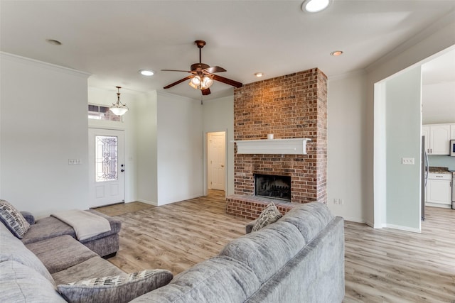 living room featuring ornamental molding, a fireplace, light wood-style flooring, and recessed lighting