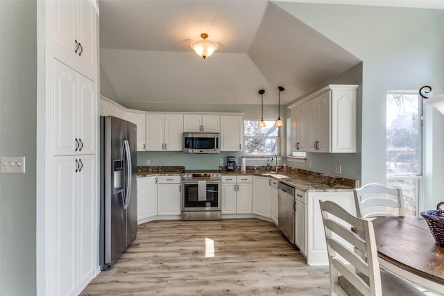 kitchen featuring white cabinets, stainless steel appliances, a sink, and lofted ceiling