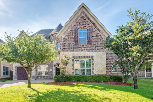 french country style house with a garage, driveway, brick siding, and a front yard