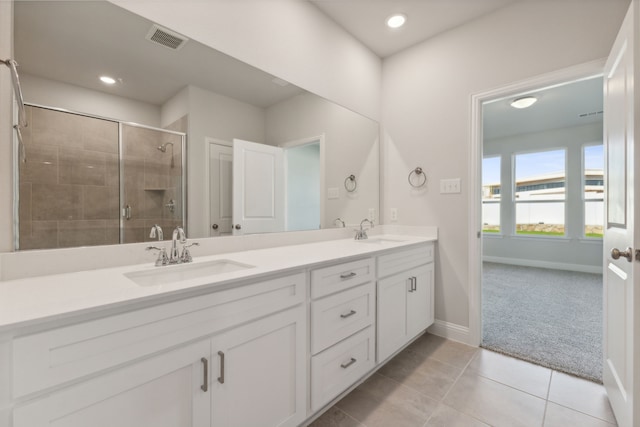 bathroom with visible vents, a sink, a shower stall, and double vanity