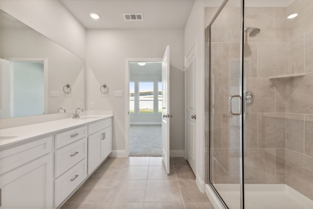 bathroom featuring tile patterned flooring, a sink, visible vents, a shower stall, and double vanity