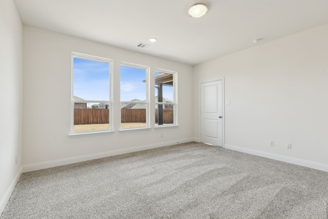 unfurnished room featuring visible vents, baseboards, and light colored carpet