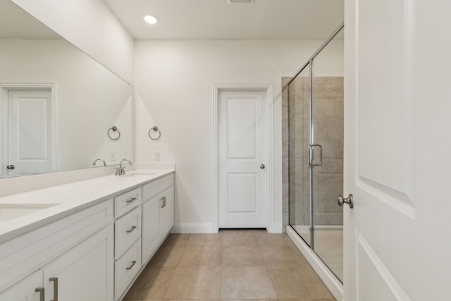full bath featuring tile patterned flooring, baseboards, double vanity, a stall shower, and a sink